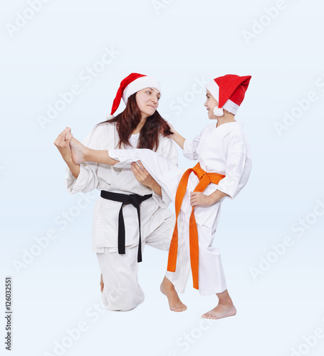 Sports family in caps of Santa Claus are training kick leg