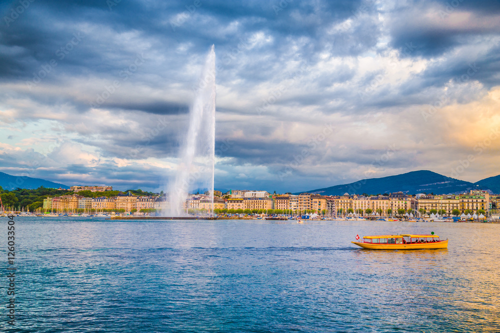 Geneva skyline with famous Jet d'Eau fountain and boat at sunset, Switzerland