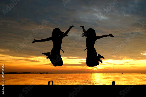 silhouette of women jumping at the sea
