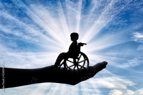 Disabled child in a wheelchair in a man's hand