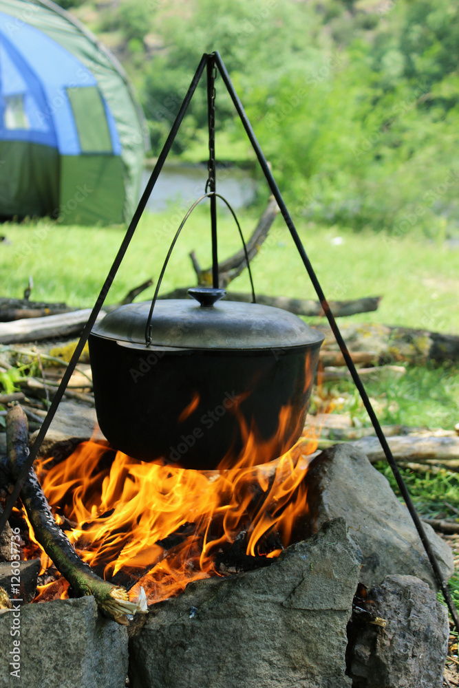 Cooking outdoors. Cauldron on a fire in the forest Cooking outdoors. Cauldron on a fire in the forest