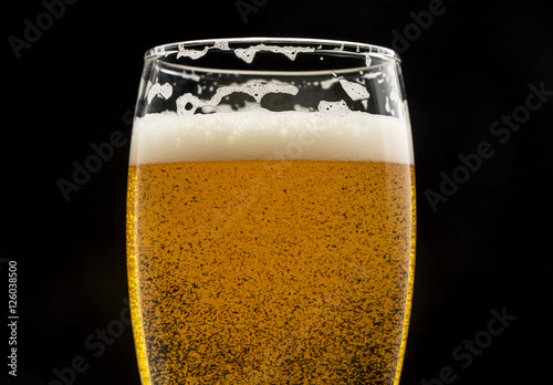Photography glass of beer with bubbles and foam on black closeup.