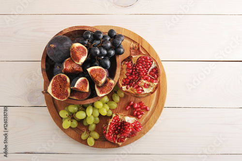 fruit platter - figs, grapes, pomegranate on wooden background photo