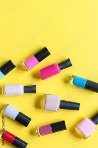 lot of bottles nail polish on yellow background top view
