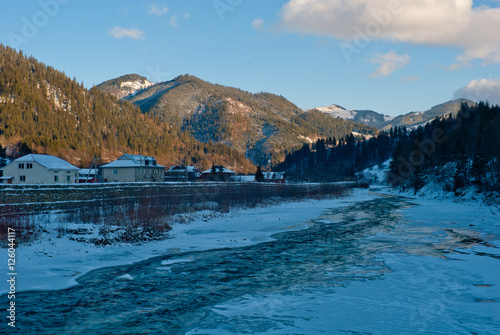 sunny winter mountain landscape with river near village houses