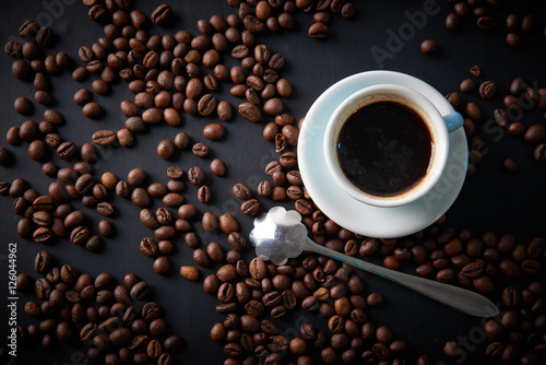 Cup of coffee and coffee beans on a black background. View from above. Shooting in studio.