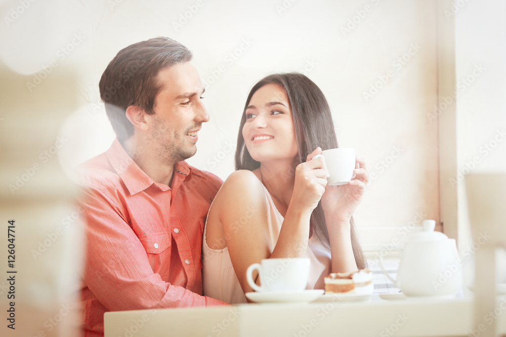 Young couple with drink in cafe. View through window glass effect. Young couple with drink in cafe. View through window glass effect.