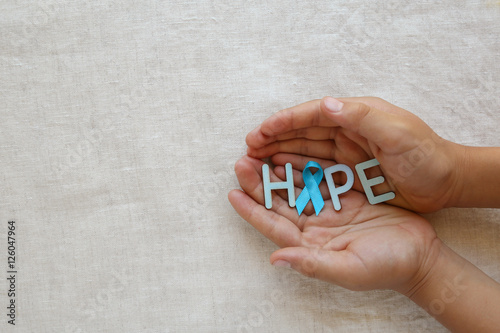 hands holding HOPE with Light blue, sky blue ribbon, copy space background, Prostate Cancer Awareness,Achalasia awareness and Adrenocortical carcinoma awareness photo