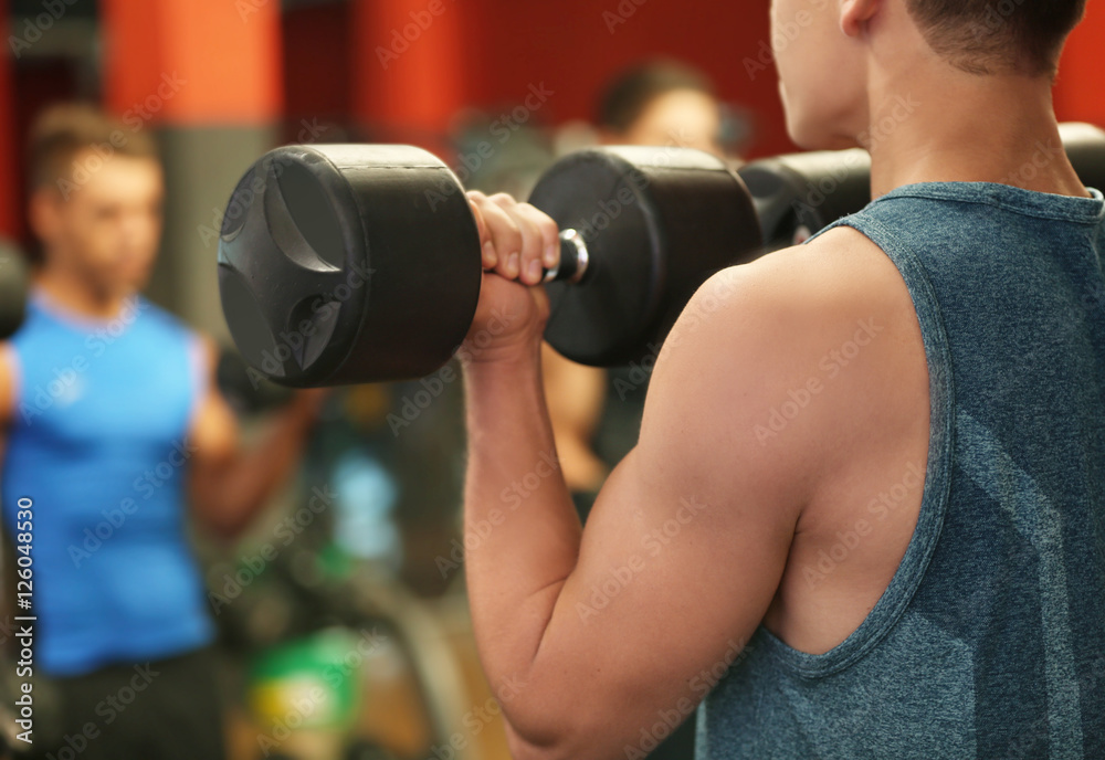 Athletic man training with dumbbells in gym