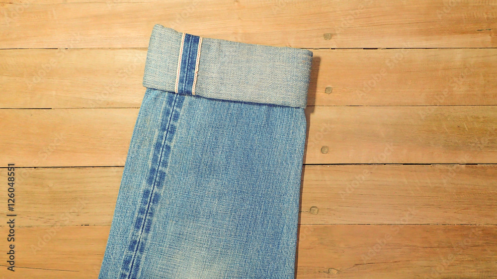 Light blue jeans and seam on a brown wooden background, copy space Light blue jeans and seam on a brown wooden background, copy space