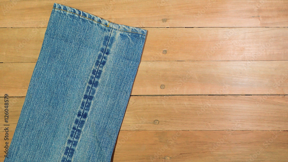Light blue jeans and seam on a brown wooden background, copy space Light blue jeans and seam on a brown wooden background, copy space