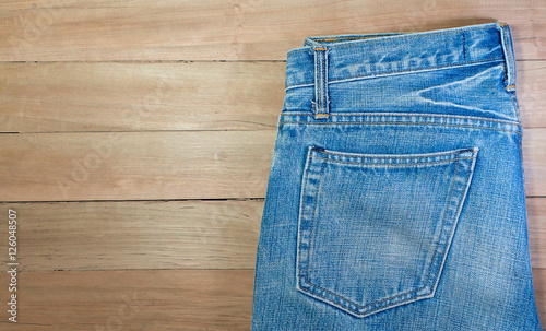 Light blue jeans, seam, and pocket on a brown wooden background, copy space