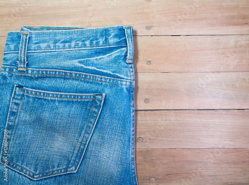 Light blue jeans, seam, and pocket on a brown wooden background, copy space