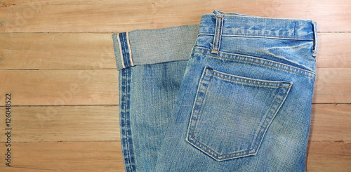 Light blue jeans, seam, and pocket on a brown wooden background, copy space