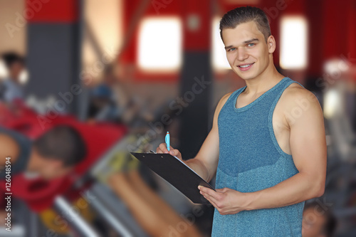 Portrait of personal trainer holding clipboard with training plan in gym