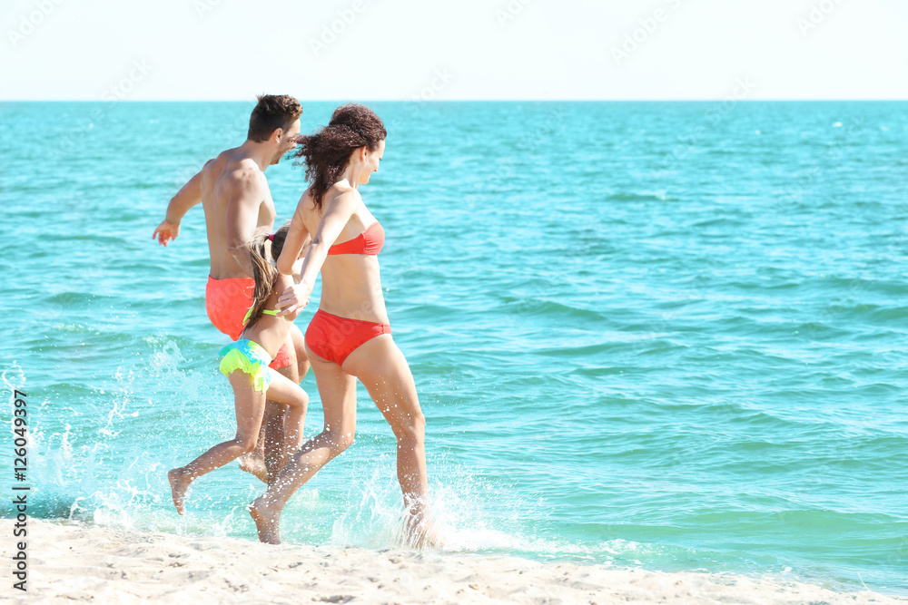 Cheerful parents playing with little girl in water