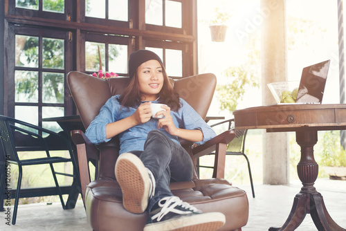 Woman raising with a coffee cup,smiles lying on the couch, sofa.