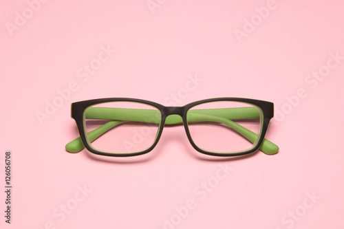 green eye glasses on pink paper background