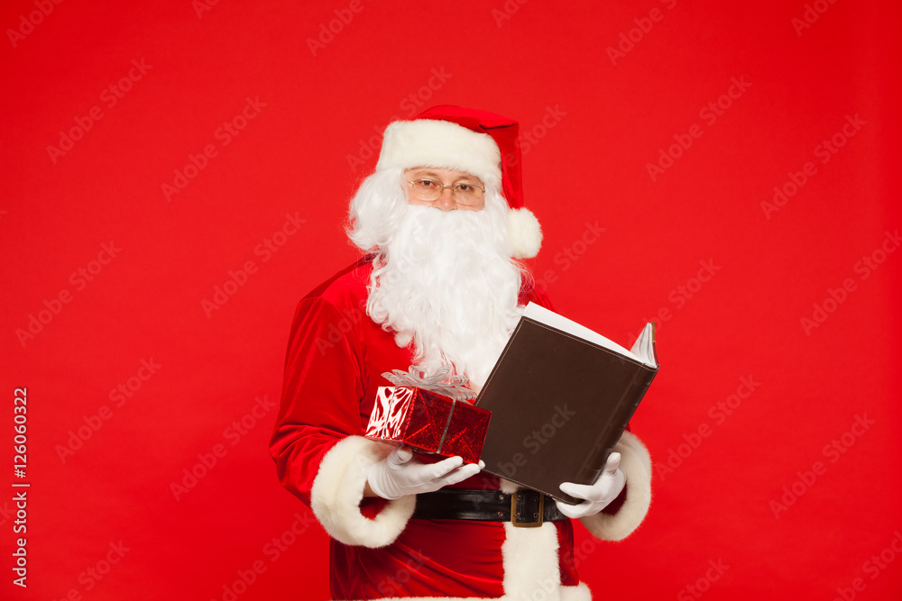 Naklejka premium Santa Claus reads old book, on a red background. Christmas