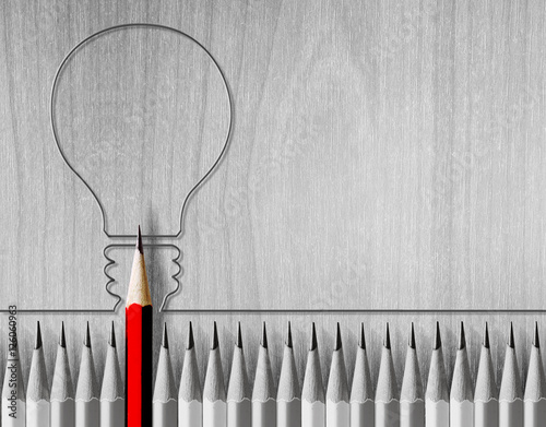 Red pencil drawing light bulb in the middle of the black and white pencil. The concept of energy