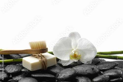 White orchid blossom with black stones  grove soap on wet background