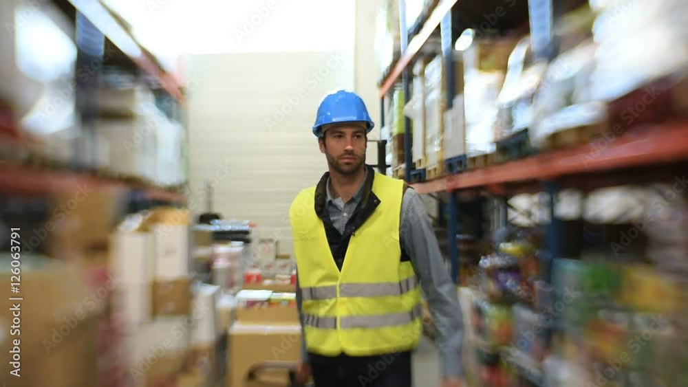 Warehouse operator pulling cart in storage aisle
