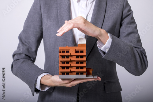 business person holds apartment building miniature model photo