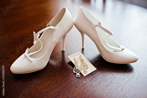 white bridal shoes with earrings on wooden table