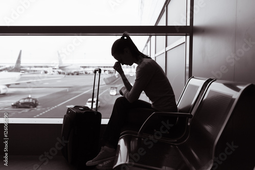 Woman sitting at airport feeling unhappy and sad. 