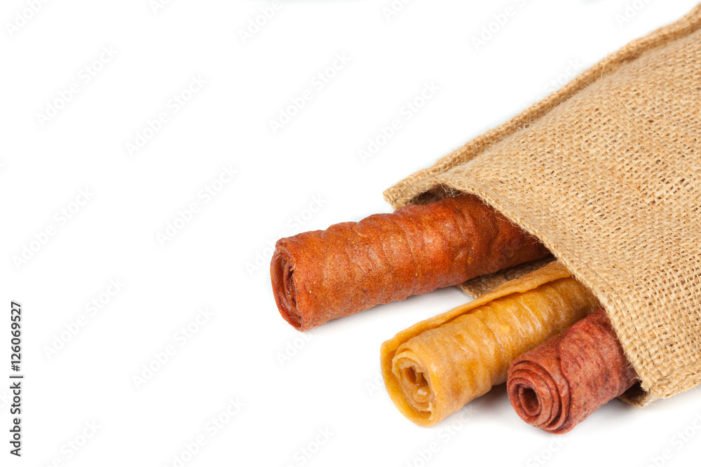 Candied fruit twisted in roll in the linen bag isolated on white background. Homemade sweetness of dried fruit.
