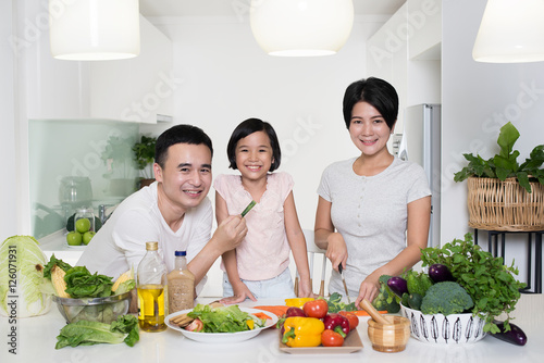 Happy Asian family preparing food in the kitchen.