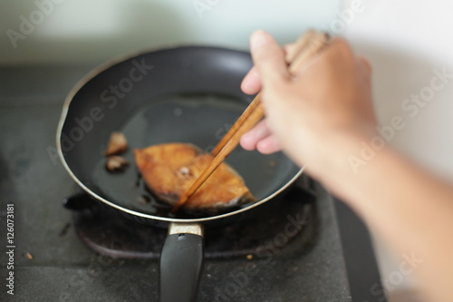 fried mackerel in black pan, little blur, slow speed, swallow deep of field