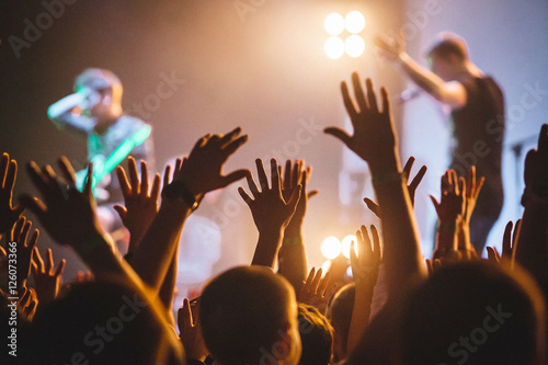 A crowd of people celebrating and partying with their hands in the air to an awesome rock artists. High ISO grainy image