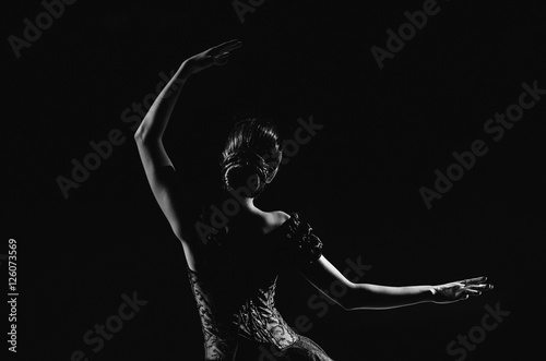 Fotobehang Light silhouette of elegant young ballerina standing back to camera in third pos