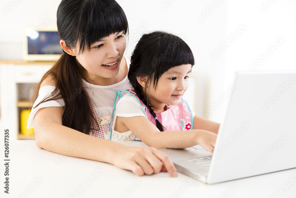 mother with little girl using laptop in the kitchen mother with little girl using laptop in the kitchen