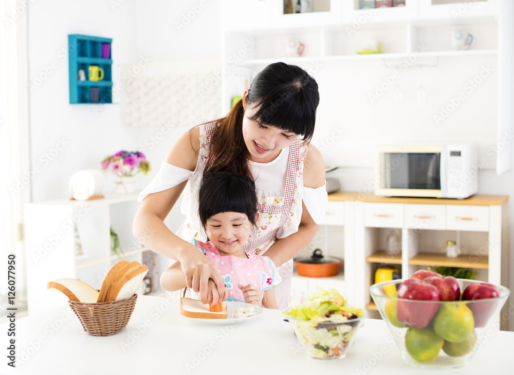 little girl helping her mother prepare food in the kitchen