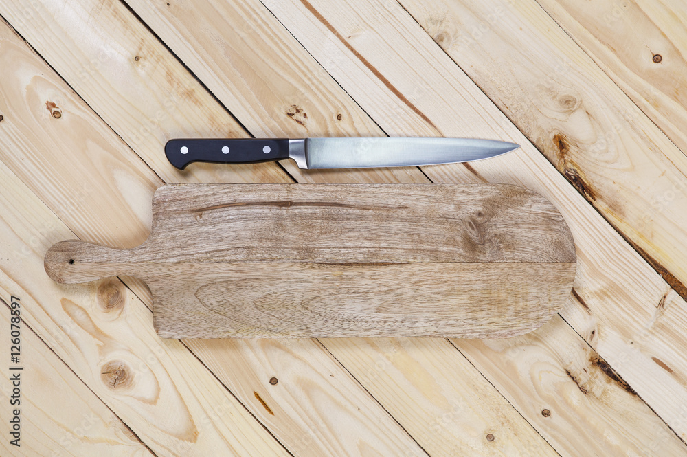 Cutting board with knife on wooden table. Top view