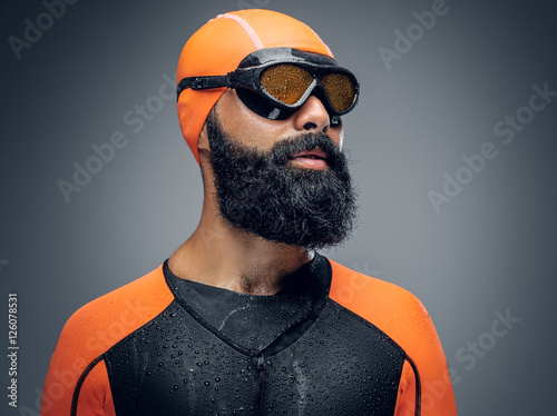 Bearded scuba diver male in orange neoprene suit isolated on gre photo