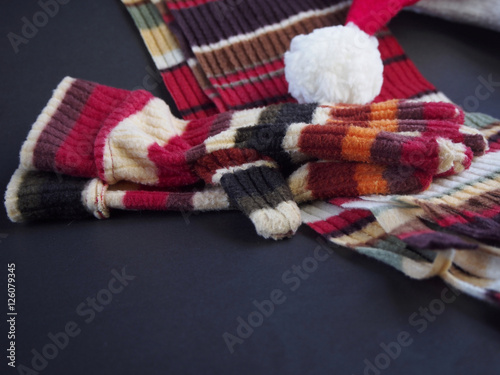 Gloves and scarf with hat of santa claus on black background