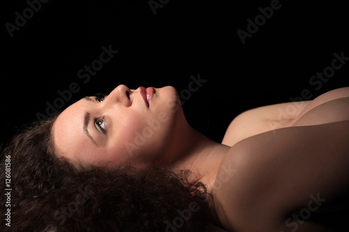 profile of a beautiful young woman with curly hair on dark background