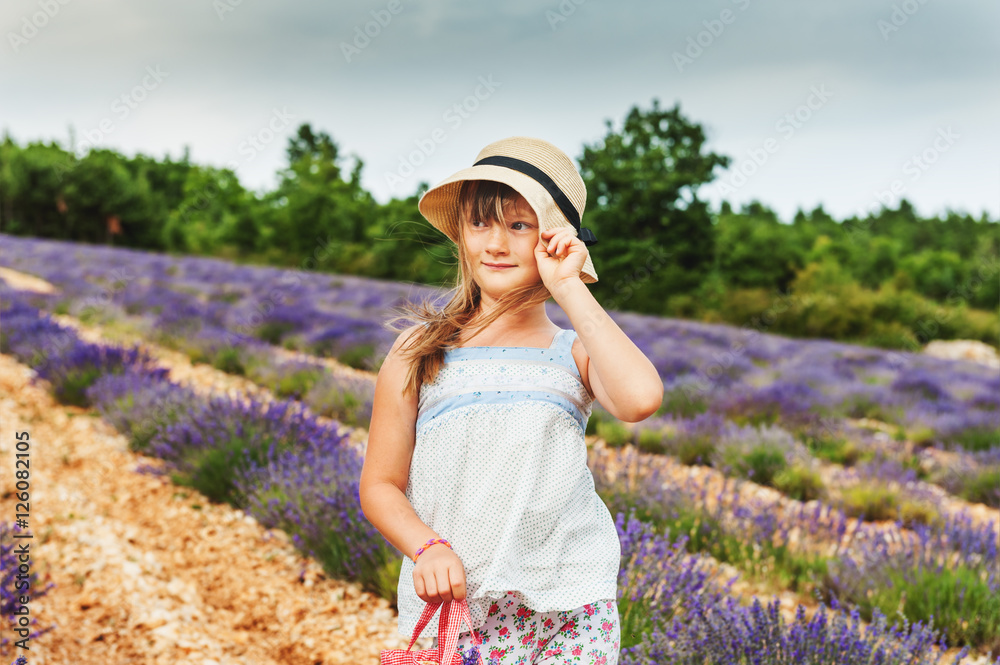 Portrait of adorable little girl wearing a hat, playing in lavender field, Provence, France