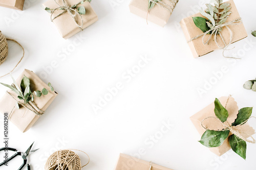 creative arrangement frame of craft boxes and green branches on white background. flat lay  top view