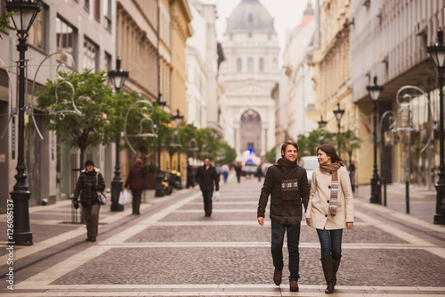 Christmas in old town. Young cheerful caucasian couple in warm cozy clothes walking in city centre.