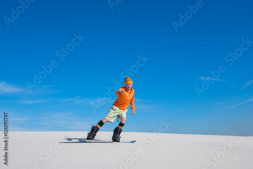 Man on snowboard, riding on sand slope.