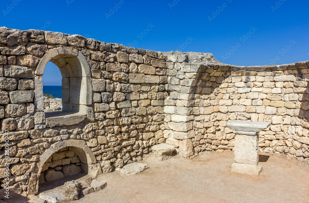 ancient stone wall with a window and a view of the sea on the ru