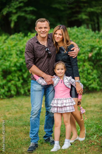 happy family embraces, walks in the park and poses in the camera, the happy daughter smiles and embraces parents © Tortuga