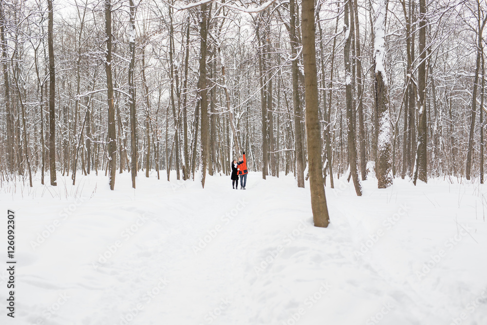 happy couple walking through a snowy forest in winter