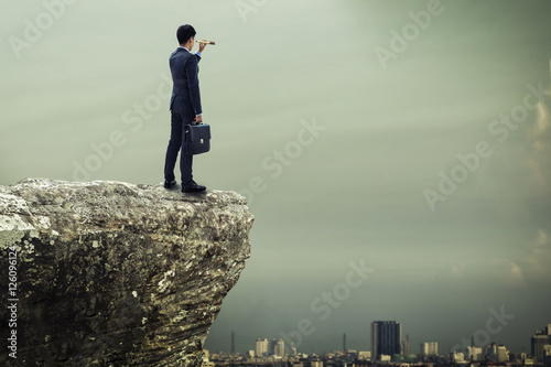 Fotografi businessman standing on the top of mountain and searching the op
