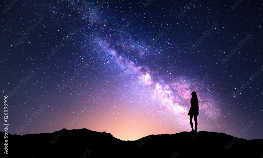 Naklejka Piękna purpurowa Droga Mleczna z stojącą kobietą. Kolorowy krajobraz z nocnym niebem z gwiazdami i sylwetką dziewczyna na górze na tle piękna galaktyka. Droga mleczna z żółtym światłem.