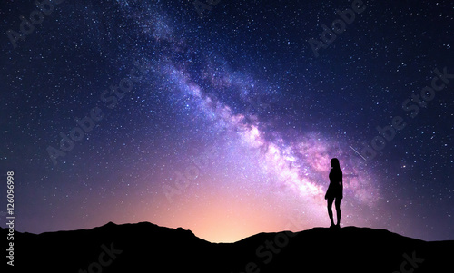 Naklejka Piękna purpurowa Droga Mleczna z stojącą kobietą. Kolorowy krajobraz z nocnym niebem z gwiazdami i sylwetką dziewczyna na górze na tle piękna galaktyka. Droga mleczna z żółtym światłem.